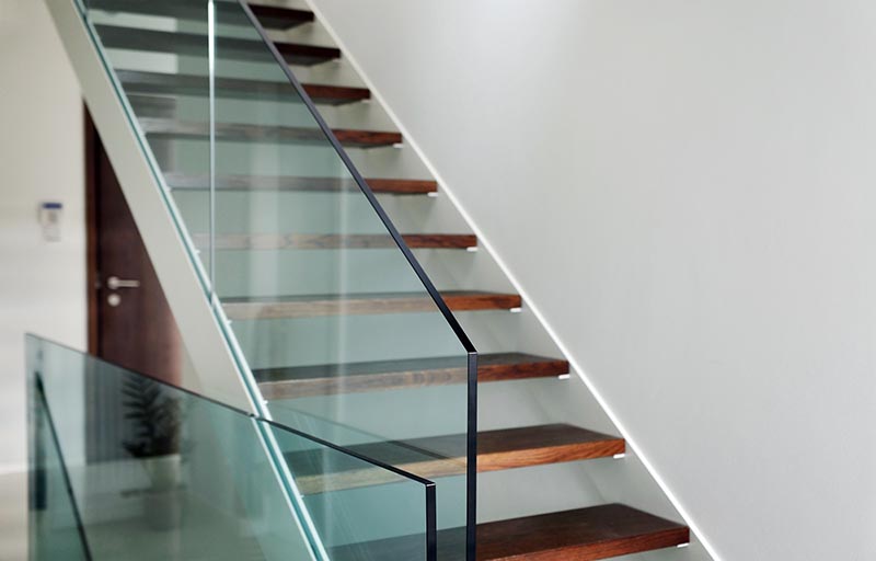 detail of hardened glass balustrade in house with wooden stairs
